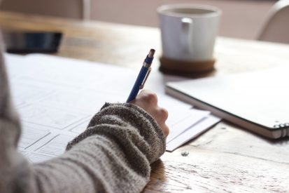 man writing down on a paper